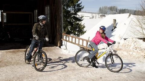 Albert und Lena auf ihren Fahrrädern im Schnee