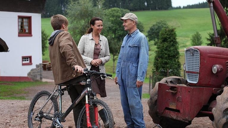 Sebastian, Sabine und Karl stehen vor dem roten Traktor hinterm Fallerhof