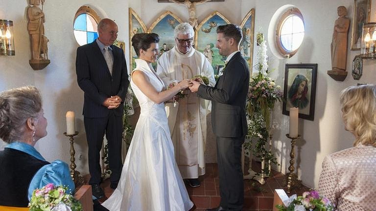 Andreas steckt Eva in der Kapelle den Ehering an den Finger