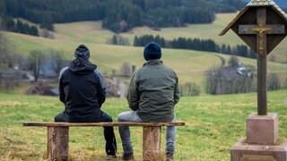 Constantin (Robert Besta) und Heinz (Thomas Meinhardt) sitzen nebeneinander auf einer Bank und blicken ins Tal