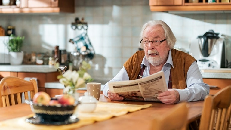 Hermann (Wolfgang Hepp) sitzt mit der Zeitung am Küchentisch