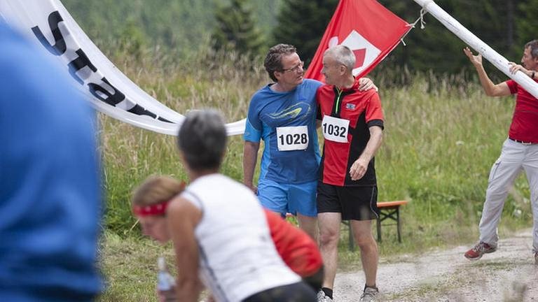 Karl und Bernhard laufen am Ende der Marathonstrecke gemeinsam über die Ziellinie