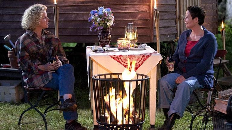 Bea und Rosi sitzen am Lagerfeuer vor Rosis Bauwagen