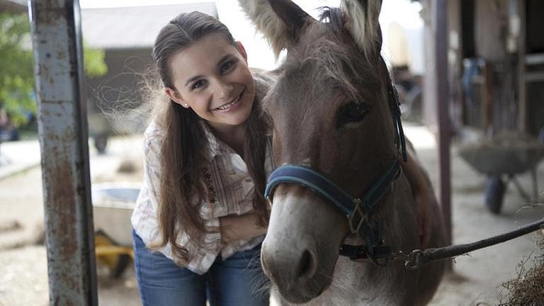 Jenny umarmt Esel Doudou und lächelt in die Kamera