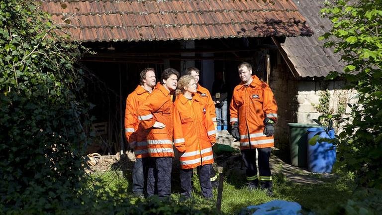 Der Feuerwehrtrupp vor einem alten Schuppen