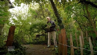 Ein Mann steht in seinem wild wuchernden Garten