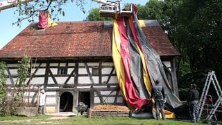 Freilichtmuseum in Neuhausen ob Eck wird mit einer Deutschlandflagge verhüllt, um die Holzwürmer zu bekämpfen.