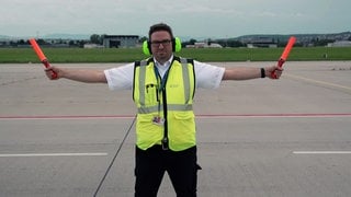 Daniel Günter ist Duty Airport Manager am Flughafen Stuttgart. er steht auf dem Rollfeld und weist ein Flugzeug ein.