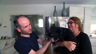 Hundefriseur Tobias Haug aus Mössingen streichelt einen Hund, der von seiner Besitzerin auf dem Arm gehalten wird.