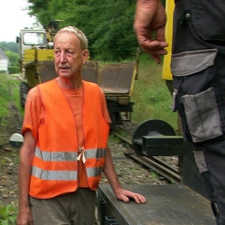 Männer des Fördervereins Welzheimer Bahn reparieren die Zugstrecke nach Welzheim. Sie tragen orangene Warnwesten.