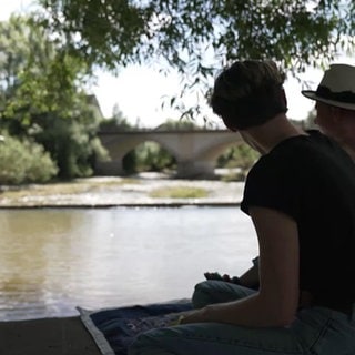 Schauspielpärchen sitzt am Fluss