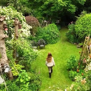 Frau läuft durch einen prächtigen Garten