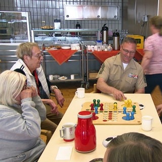 US Marines aus Böblingen zu Besuch in einem Altenheim in Zuffenhausen. Sie sitzen am Tisch und spielen mit Bewohnern Mensch-ärgere-dich-nicht.