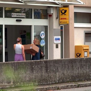 Zwei Frauen mit einemPaket stehen an der Tür der Post-Agentur in Blaustein