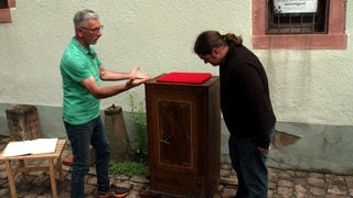 Zwei Männer stehen neben einem Tresor, der vom Heimatmuseum in Epfenbach versteigert wird