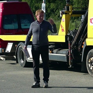 Siggi Faller steht auf dem Parkplatz seines Rasthofs "Fallerhof" an der A5 bei Bad Krozingen und winkt einen Bus ein.