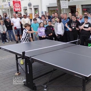 Viele Menschen sehen zwei Personen beim Tischtennis spielen zu