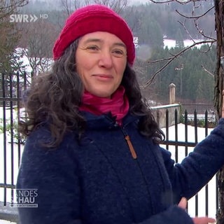 eine Frau steht an einem Baum