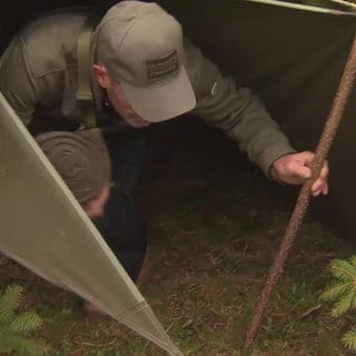 Mann steigt aus einem kleinen Zelt