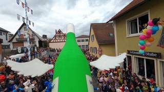 Ein Motivwagen einer Flasche auf einem Umzug. 