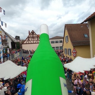 Ein Motivwagen einer Flasche auf einem Umzug. 