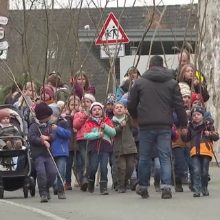 Kinder laufen auf der Straße mit Stöcken am Bärensonntag