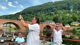 Bootsfahrt auf dem Neckar in Heidelberg: Touristen fotografieren Sehenswürdigkeiten