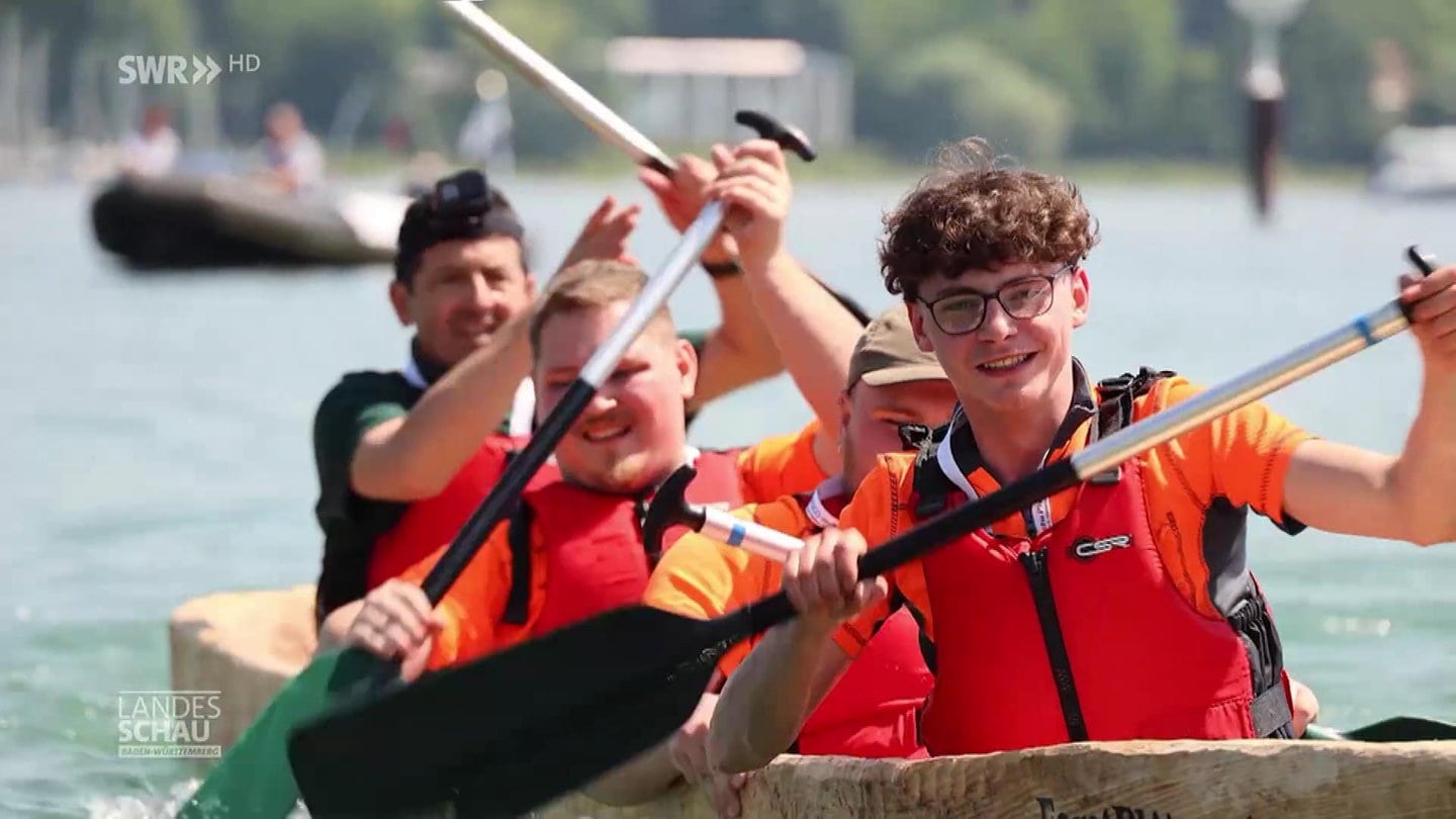 Junge Teilnehmer einer Einbaum-Regatta auf ihrem Boot im Wasser