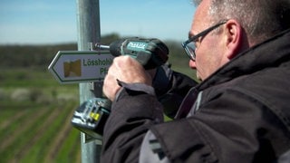 Karl Küchle repariert ein Schild in den Weinbergen am Kaiserstuhl