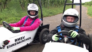 Zwei Frauen sitzen mit Helm in zwei weißen Wägen 