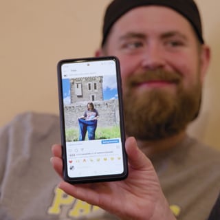 Instagram-Seite auf Handy. Ein Mann sitzt im Hintergrund