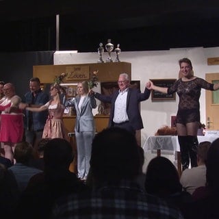 Bürgermeister und andere Personen auf Bühne bei Theateraufführung