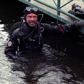 Golfballtaucher Sven ist im Taucheranzug im Wasser