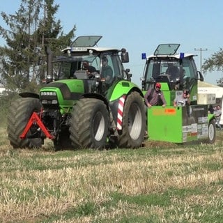 Ein Traktor zieht einen Bremswagen über einen Acker