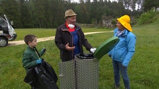 Mann leert Mülleimer im Wental