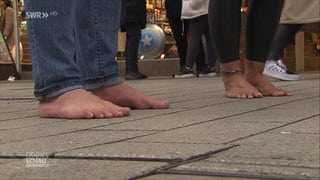 Daisy und Alex barfuß vor einem Schuhgeschäft