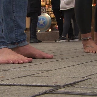 Daisy und Alex barfuß vor einem Schuhgeschäft