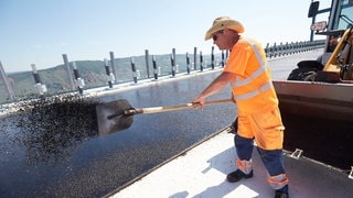 Ein Bauarbeiter mit Sonnenhut arbeitet mit einer Schaufel