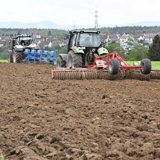 Landwirte bearbeiten mit Hilfe von Traktoren ein Feld.