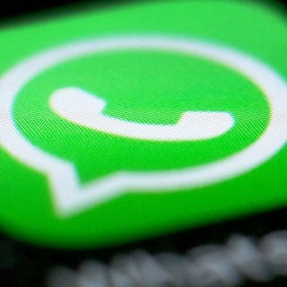 Das Logo der Messenger-App WhatsApp ist auf dem Display eines Smartphones zu sehen.