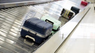 Koffer liegen auf einem Gepäckband am Flughafen. Welche Rechte haben Flugpassagiere, wenn ihr Gepäck nicht ankommt, verspätet ankommt oder beschädigt ist?