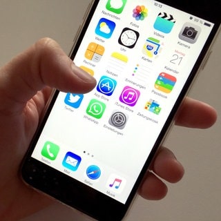 Auf dem Display eines Apple iPhone sind Symbole verschiedener Apps zu sehen. 