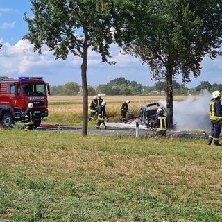 Feuerwehrleute löschen das Unfallwrack eines E-Autos. 