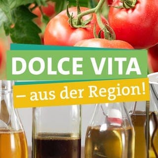 In der rechten Bildhälfte hält Ökochecker Joti einen Teller veganes Hack in den Händen. Links schaut Ökochecker Tobi fragend. Davor steht "Dolce Vita" "–  aus der Region" geschrieben, jeweils unterlegt von farbigen Bändern. Im Hintergrund sind Tomaten und Ölflaschen zu erkennen.