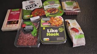 Aus einer Küchen-Oberfläche liegen mehrere Fleischersatzprodukte. Es gibt veganes Hack aus Seitan, aus Sonnenblumenkernen von der Eigenmarke von Rossmann und Hack auf Soja-Basis von Rügenwalder Mühle.