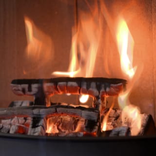 Brennende Holzbalken in einem Kamin: Das Feuer schlägt hohe Flammen.