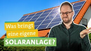 Im Hintergrund ist ein Haus zu sehen, dessen Dach vollständig mit einer Photovoltaikanlage bedeckt ist. Die Sonne scheint und erzeugt somit Strom. Ökochecker Tobi steht rechts im Vordergrund und schaut fragend. Links steht der Titel gelb und grün unterlegt: Lohnt sich eine eigene Solaranlage?