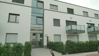 Klimaneutral gebautes Mehrfamilienhaus auf drei Stockwerken - Außenansicht mit Balkonen.