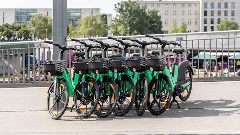 Mehrere grüne E-Bikes stehen aneinander gelehnt am Straßenrand. 