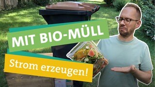 Was lässt sich alles aus Bio-Müll machen? Ökochecker Tobias Koch in der linken Bildhälfte schaut fragend auf eine Vorratsbox aus durchsichtigem Plastik  voller Bio-Müll in seiner rechten Hand. Im Hintergrund erkennt man eine Biotonne in einem länglichen Garten. Daneben steht eine hölzerne Wurmkiste. Unterlegt von je einem farbigen Band auf dem "MIT BIO-MÜLL" "Strom erzeugen!" steht.